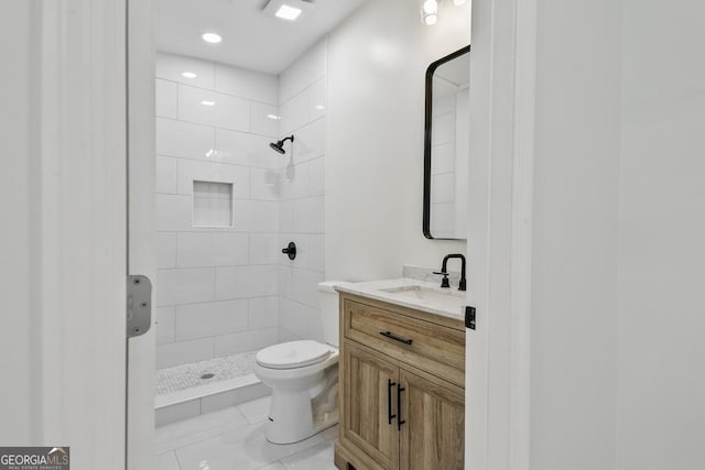 bathroom featuring tile patterned floors, vanity, toilet, and a tile shower