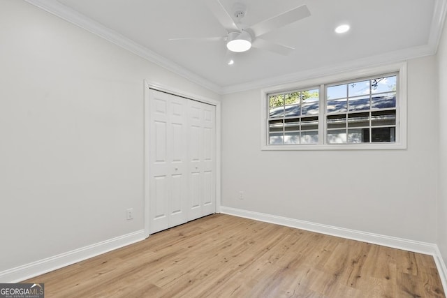 unfurnished bedroom with ceiling fan, a closet, crown molding, and light wood-type flooring