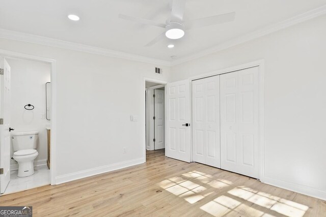 unfurnished bedroom with ensuite bathroom, crown molding, ceiling fan, light hardwood / wood-style floors, and a closet