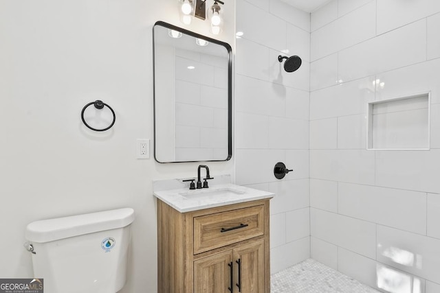 bathroom featuring tiled shower, vanity, and toilet