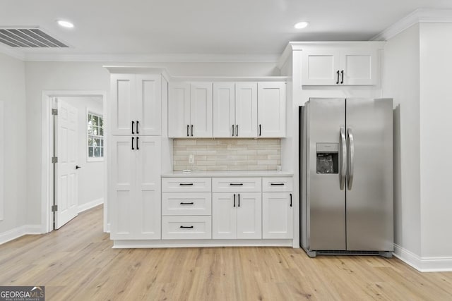 kitchen featuring white cabinets, stainless steel fridge, decorative backsplash, and ornamental molding