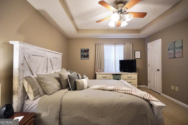 carpeted bedroom featuring a textured ceiling, a tray ceiling, and ceiling fan