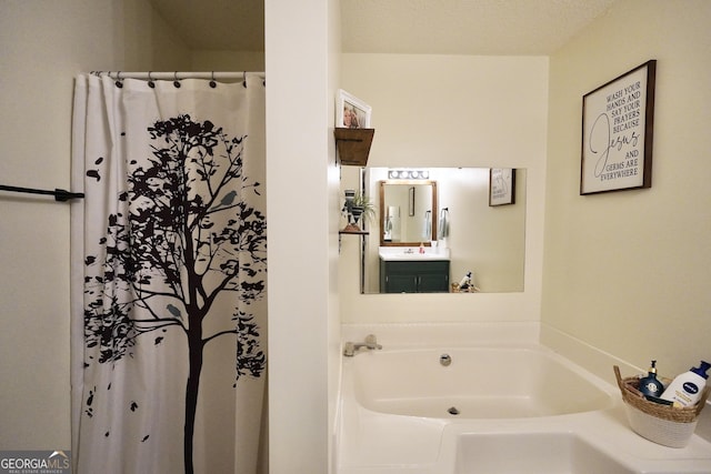 bathroom with vanity, a textured ceiling, and a tub