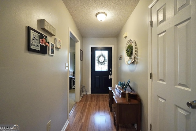 doorway to outside featuring wood-type flooring and a textured ceiling