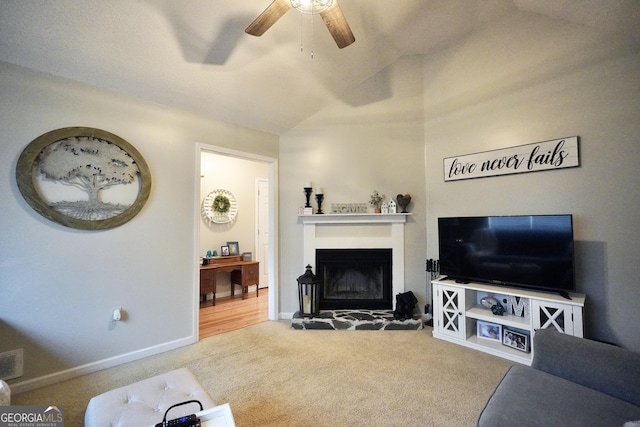 living room with carpet flooring, vaulted ceiling, and a stone fireplace