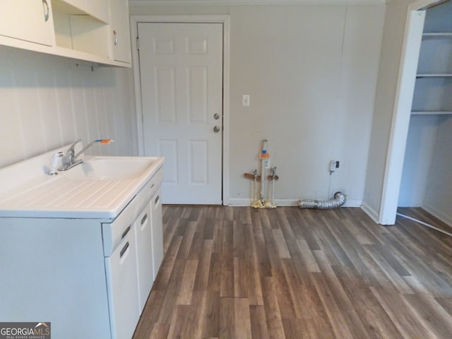 clothes washing area with a sink, dark wood finished floors, cabinet space, and baseboards