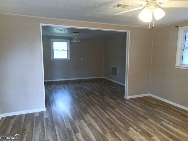 empty room featuring ceiling fan, dark wood finished floors, and visible vents