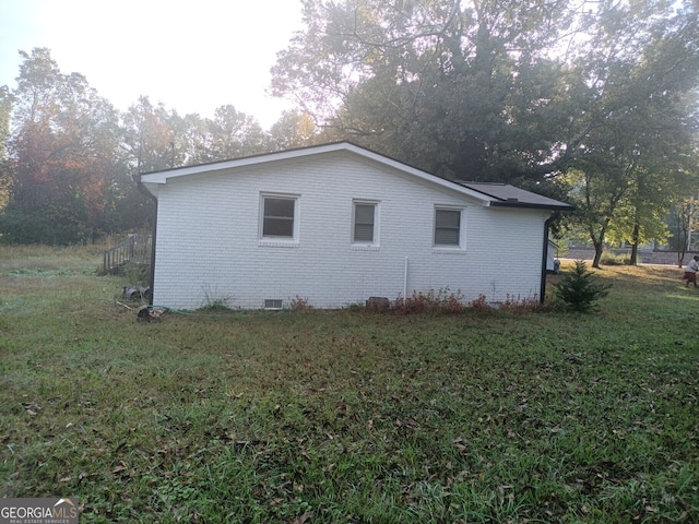 view of side of home featuring crawl space, brick siding, and a yard