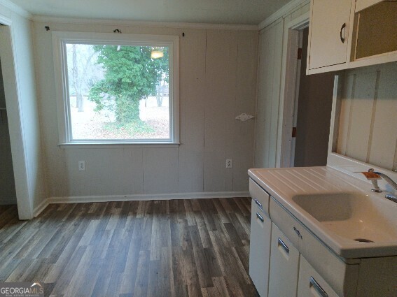 kitchen with dark wood-type flooring, a sink, baseboards, white cabinets, and light countertops