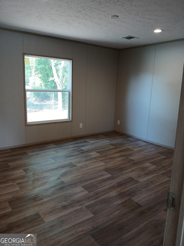 spare room with a textured ceiling and dark wood-type flooring