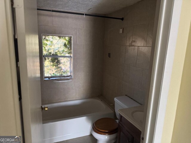 full bathroom with tiled shower / bath combo, tile patterned flooring, a textured ceiling, toilet, and vanity