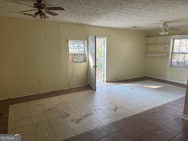 unfurnished room featuring cooling unit, a healthy amount of sunlight, and a textured ceiling