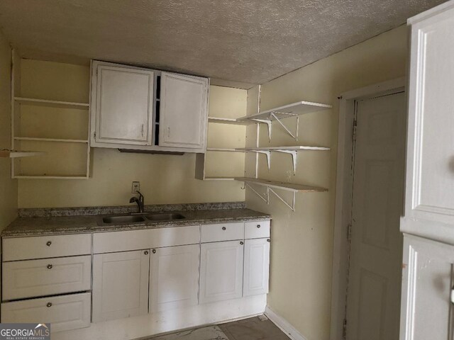 kitchen featuring white cabinetry, sink, and a textured ceiling