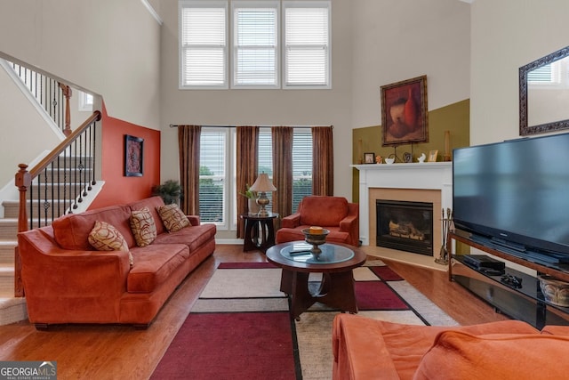 living room with a towering ceiling, a healthy amount of sunlight, and light hardwood / wood-style floors