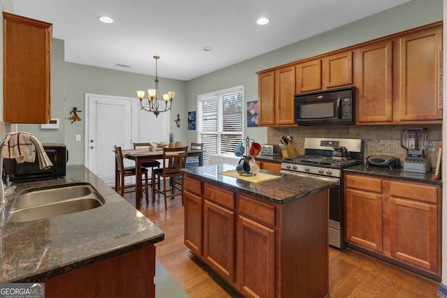 kitchen with gas stove, decorative light fixtures, a chandelier, a center island, and light hardwood / wood-style floors