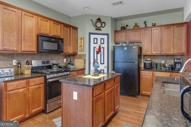 kitchen with decorative backsplash, a center island, black appliances, and light hardwood / wood-style flooring