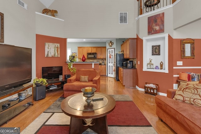 living room featuring high vaulted ceiling and light hardwood / wood-style flooring