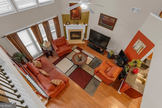 living room with ceiling fan, a towering ceiling, and hardwood / wood-style flooring