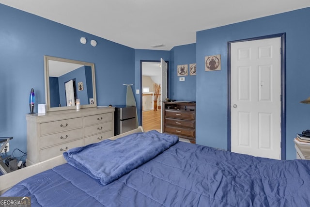 bedroom featuring hardwood / wood-style flooring and stainless steel fridge