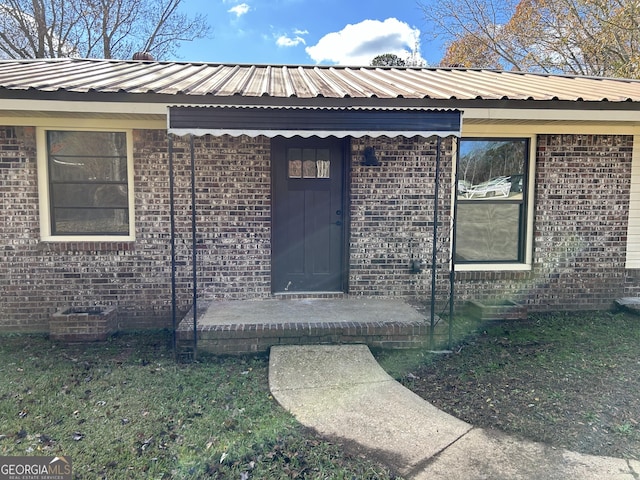 view of exterior entry featuring a lawn