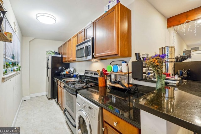 kitchen with sink, stainless steel appliances, kitchen peninsula, dark stone counters, and washer / dryer