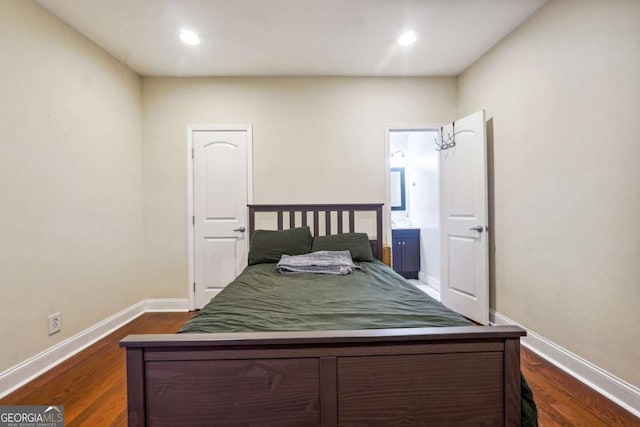 bedroom with ensuite bathroom and dark wood-type flooring