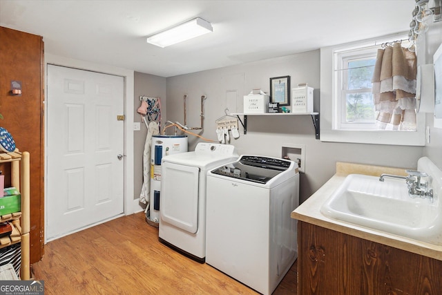 washroom featuring light hardwood / wood-style floors, electric water heater, sink, and separate washer and dryer