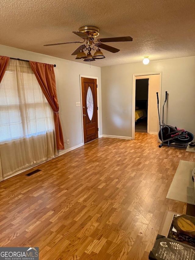 foyer entrance featuring ceiling fan, a textured ceiling, and light wood-type flooring