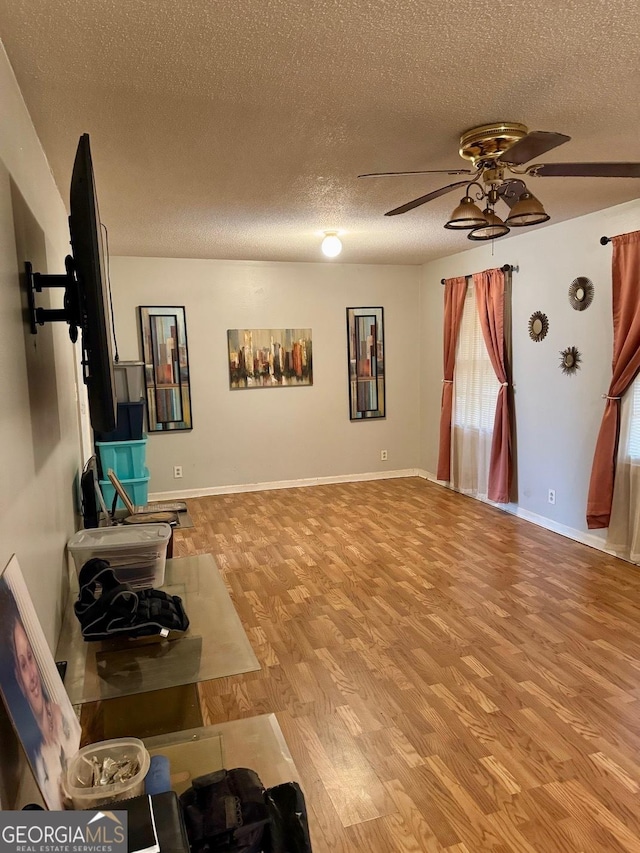 living room featuring light wood-type flooring, a textured ceiling, and ceiling fan