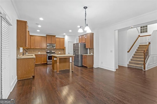 kitchen featuring dark wood-type flooring, sink, appliances with stainless steel finishes, decorative light fixtures, and a kitchen island