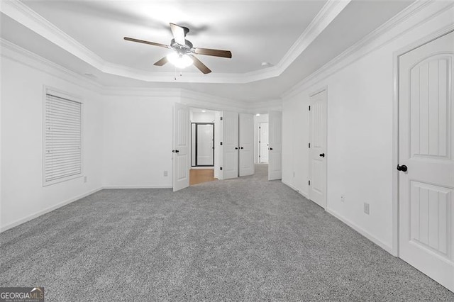 unfurnished bedroom with a tray ceiling, crown molding, carpet flooring, and ceiling fan