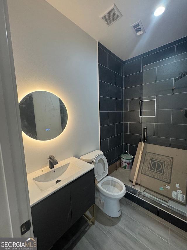 full bathroom featuring toilet, vanity, a shower stall, and visible vents