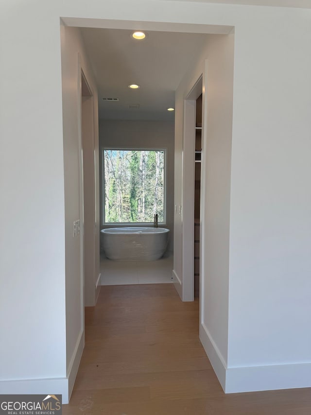 corridor featuring baseboards, wood finished floors, and recessed lighting