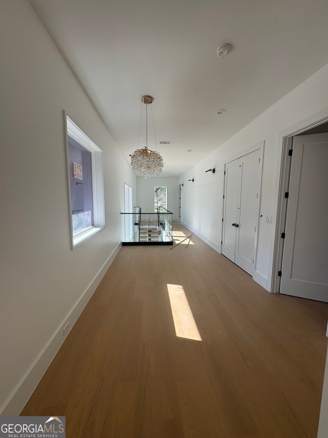 interior space featuring baseboards, visible vents, wood finished floors, and a notable chandelier