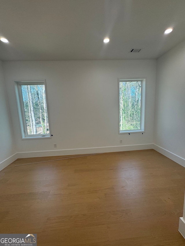empty room with baseboards, light wood-style flooring, visible vents, and recessed lighting