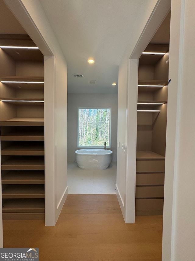 interior space with a freestanding bath, visible vents, wood finished floors, and recessed lighting