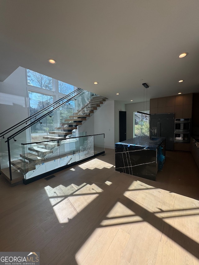 living room with wood finished floors, a healthy amount of sunlight, stairway, and recessed lighting