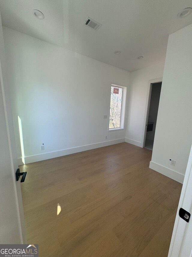 unfurnished room with wood finished floors, baseboards, and visible vents