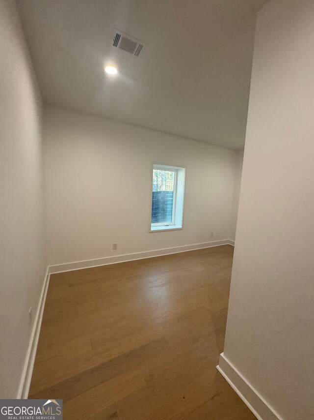 spare room with baseboards, visible vents, and wood finished floors