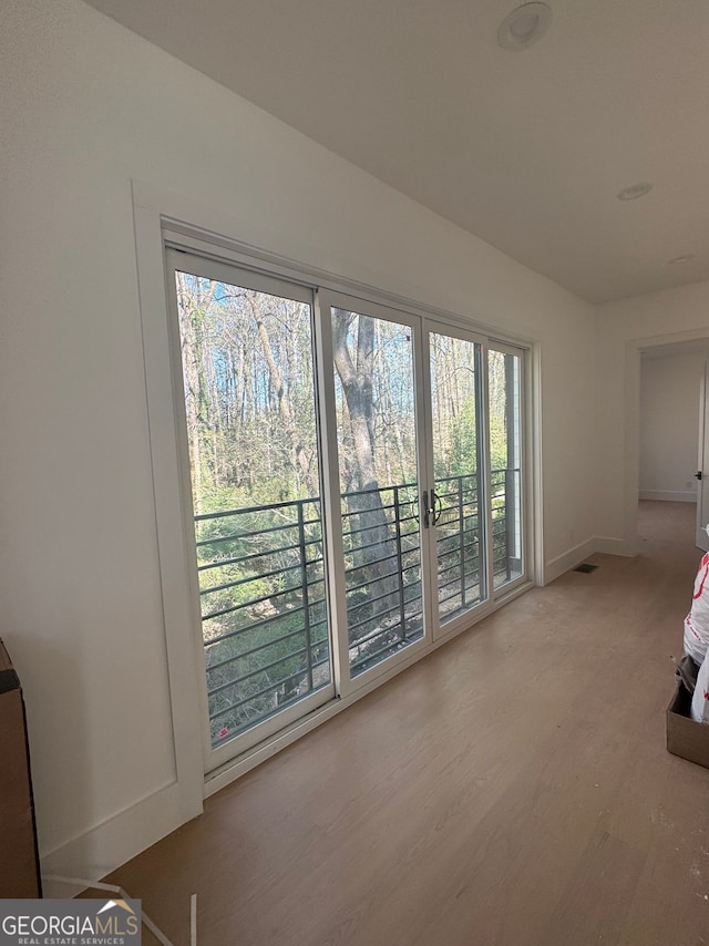 unfurnished bedroom featuring baseboards, visible vents, access to exterior, and wood finished floors