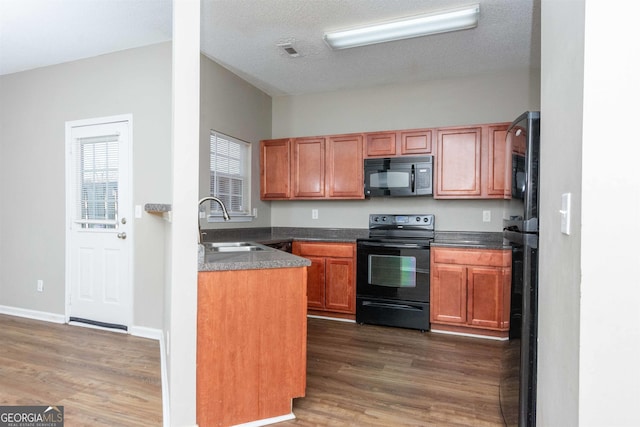 kitchen with black appliances, sink, dark wood-type flooring, and a textured ceiling