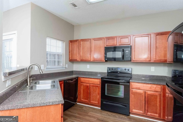 kitchen with black appliances, dark hardwood / wood-style flooring, sink, and a textured ceiling