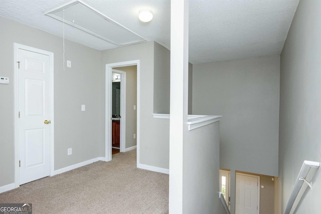 hall featuring light carpet and a textured ceiling