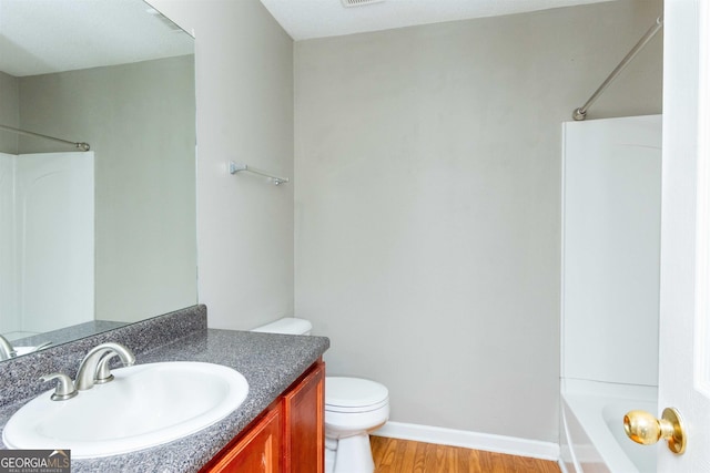 full bathroom featuring hardwood / wood-style floors, vanity,  shower combination, and toilet