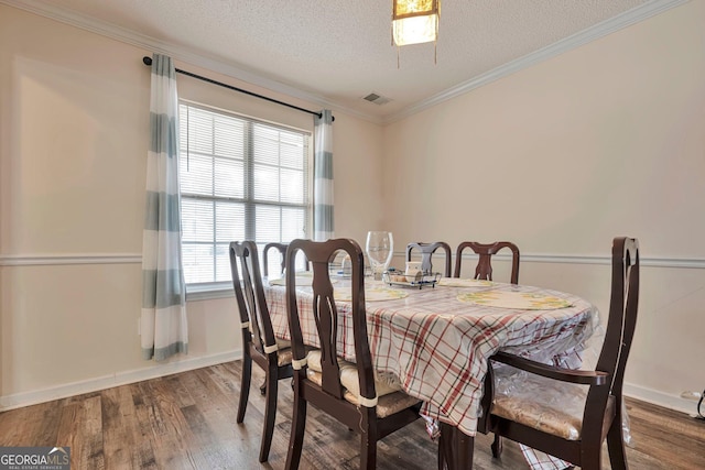 dining area with wood-type flooring, a textured ceiling, and ornamental molding