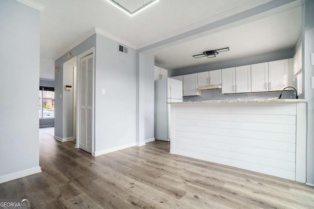 kitchen featuring white cabinetry, white refrigerator, kitchen peninsula, hardwood / wood-style flooring, and ornamental molding