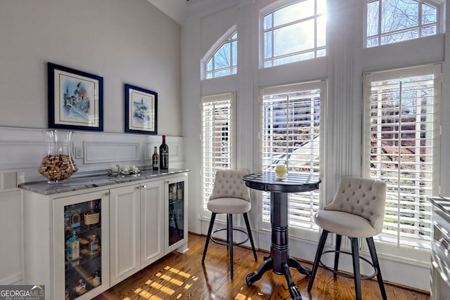 bar with white cabinets, beverage cooler, light hardwood / wood-style floors, and a healthy amount of sunlight