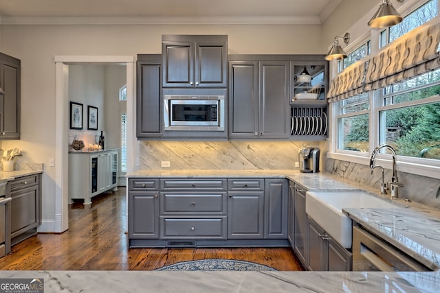 kitchen with sink, light stone counters, backsplash, gray cabinets, and stainless steel microwave