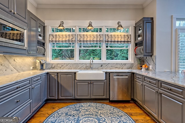 kitchen with sink, stainless steel appliances, light stone counters, tasteful backsplash, and gray cabinetry