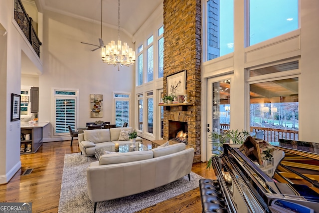 living room with a high ceiling, dark wood-type flooring, a chandelier, and a fireplace